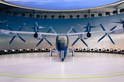 Protótipo de aeronave elétrica com hélices, visto de frente em uma área interna de exposição.