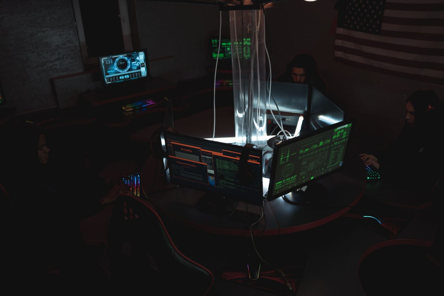 Equipe de especialistas em cibersegurança trabalhando diante de computadores em uma sala escura.