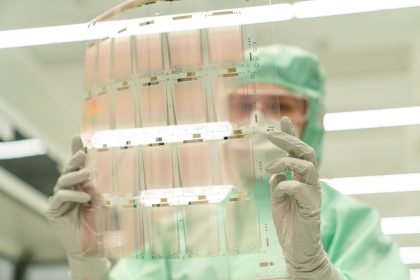 Cientista usando traje de proteção segura uma lâmina transparente em um laboratório de pesquisa tecnológica.