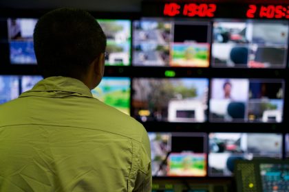Profissional observa várias telas com imagens de monitoramento em uma central de controle.