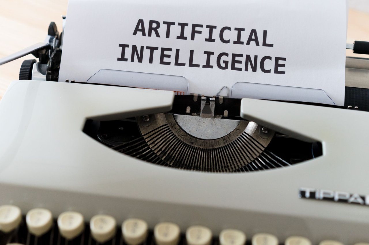 Máquina de escrever com as palavras “ARTIFICIAL INTELLIGENCE” impressas em uma folha de papel.